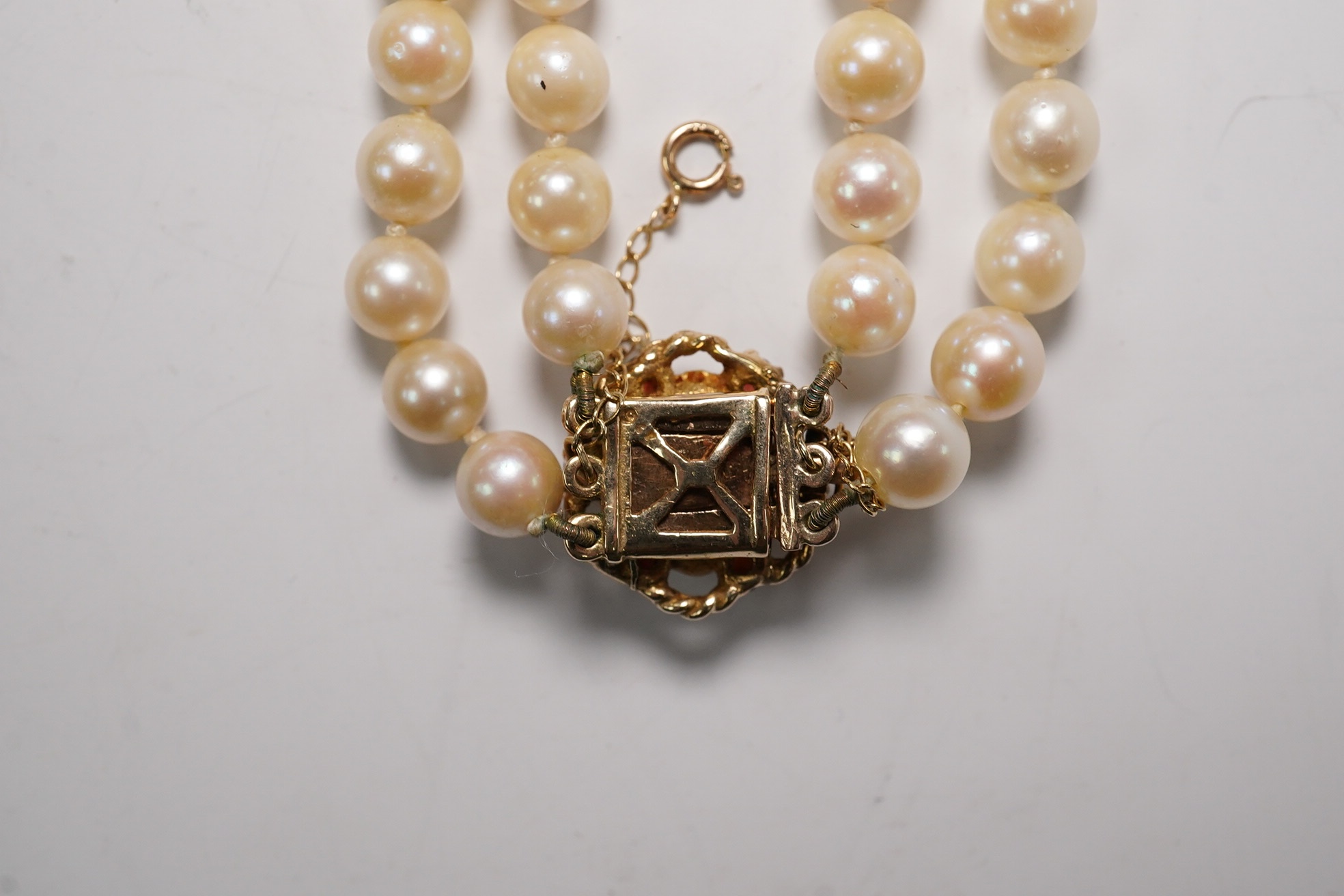 A twin strand cultured pearl choker necklace, with gem set spacers and 9ct, garnet and cultured pearl set clasp, 37cm. Condition - fair to good